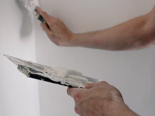 Stukadoor van Eren Afbouw werkt een wand glad af met een spaan