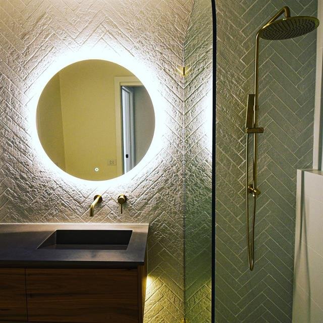 Moderne badkamer met verlichte spiegel en tegelwerk van Eren Afbouw